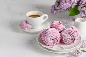 Homemade currant marshmallows  or zephyr with a cup of espresso coffee on a white table with lilacs. Selective focus. Copy space