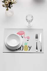 Subject photo of setting table. Plates, a fork and a knife are located near a short glass and a...