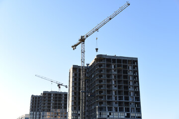 Tower crane lifting concrete bucket for pouring concrete during construction residential building on blue sky background. Builder workers during formwork and pouring concrete. New skyscraper