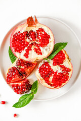 Red pomegranate on a white background. Grenades are scattered on the table. Pomegranate berries glisten on a white background.