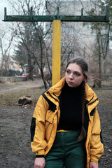 Fototapeta premium Bad girl bully in yellow coat in the backyard. Outdoor lifestyle portrait
