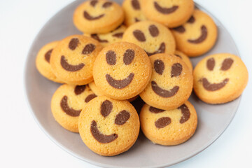 A set of smiling biscuit cookies served on brown plate isolated on white background with copy space. Smile concept. Sweet greeting