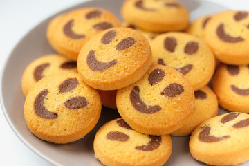 A set of smiling biscuit cookies served on brown plate isolated on white background with copy space. Smile concept. Sweet greeting