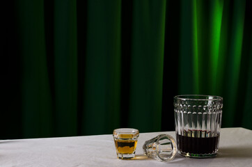 Glasses of sweet cognac and red wine on the table against green curtains.White tablecloth and alcohol drinks on the table.Empty space