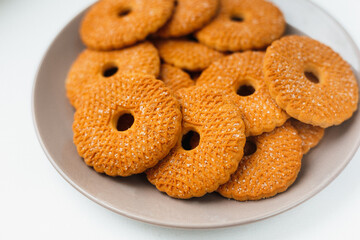 A pile of round biscuits with sugar icing  served on a brown plate isolated on white background top  side view