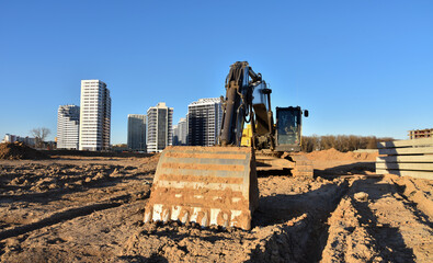 Excavators at earthworks on construction site. Backhoe loader digs a pit for the construction of...