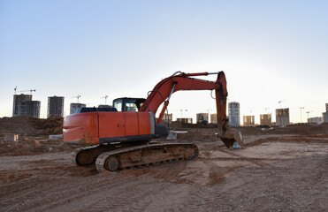Excavator working at construction site on earthworks. Backhoe on road work digs ground. Paving out...