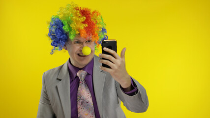Clown businessman entrepreneur in wig using app on smartphone for online work