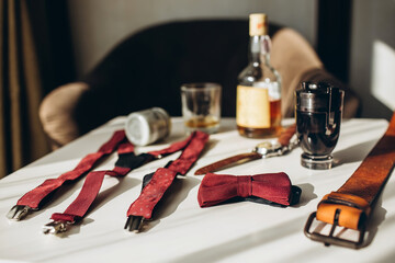 Men's accessories, leather belt, perfume, bow tie, groom's golden rings, watches and brides on a white table. Businessman clothing detail concept