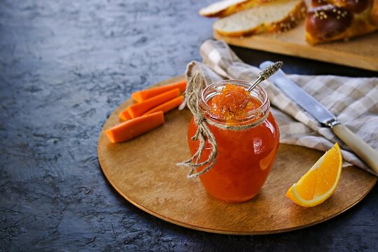 Carrot jam with orange in a glass jar on a black concrete background. Vegetable jams. Preservation, harvest.