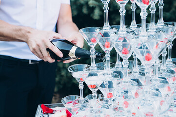 pyramid of champagne glasses at an outdoor celebration. A glass of champagne with a cherry.