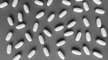 Tablets on grey background. Monochrome simple flat lay with pastel texture. Medical concept. Stock photo.