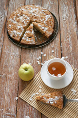 Pile of small homemade pancakes with honey, tea cup and honeycomb on wooden table