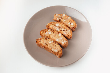 Popular Italian Biscotti or Cantucci biscuit cookies stuffed with nuts on brown plate with copy space.