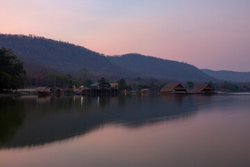 Fototapeta na wymiar Bamboo houses with mountain on the calm lake backgroud in the morning at Khao wong reservoir, Suphanburi province, Thailand