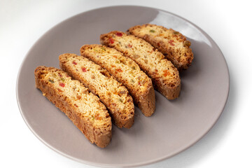 Popular Italian Biscotti or Cantucci biscuit cookies stuffed with candied fruit served on brown plate with copy space.