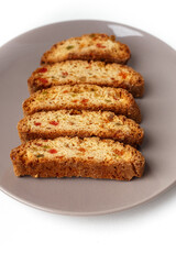 Popular Italian Biscotti or Cantucci biscuit cookies stuffed with candied fruit served on brown plate with copy space.