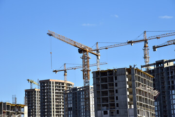 Tower cranes constructing a new residential build. Luffing jib tower crane and workers being poured concrete into formwork of building at construction site. Cement pouring