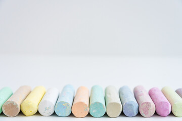 Round colored crayons are arranged in a row. Front view. White background. Spectrum.