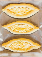 Harvest of khachapuri in Adjara on baking paper on a baking sheet