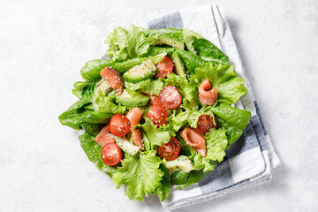 Salmon salad with avocado, green leaves, tomatoes on white background