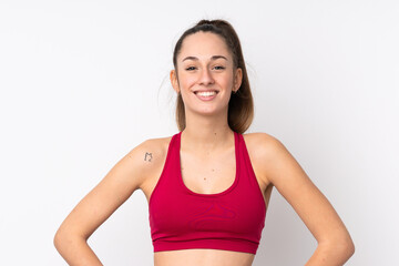 Fototapeta na wymiar Young sport brunette woman over isolated white background posing with arms at hip and smiling