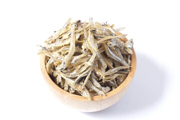 A small fish drying in a wooden cup on a white ground. Herringbone is a food with calcium that are very useful to humans.