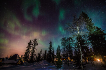 Northern lights shine over a winter landscape at night