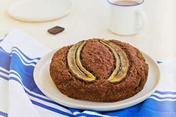 Banana bread with oatmeal and cocoa on a white ceramic plate on a light concrete background. American cuisine. Baking with banana recipes.