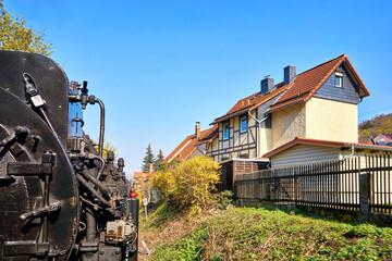 Steam locomotive drives past a half-timbered house in the city of Wernigerode. Dynamic due to motion blur.