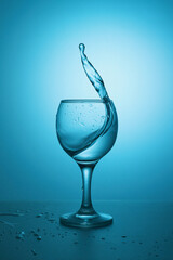 Water splashing in the luxury wine glass close up. Concept of good healthy and refreshment. Copy space on left side on the image.