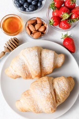 Breakfast with fresh croissants and berries on white table background