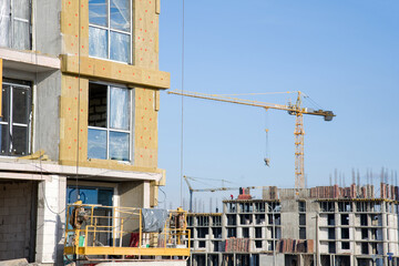 Suspended cradle/mobile scaffolding platform for construction work at height. Mineral wool for insulation of the facade building. Insulation for thermal protection to the shell of the house.