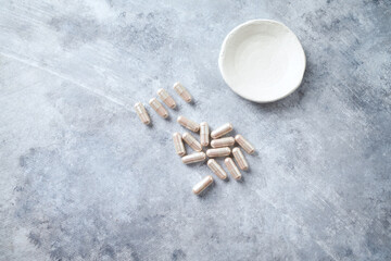 Carnitine capsules. Concept for a healthy dietary supplementation. Bright stone background. Top view. 