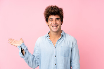 Young caucasian man with jean shirt over isolated pink background holding copyspace imaginary on...