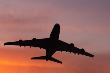 Black silhouette of plane on sunset background