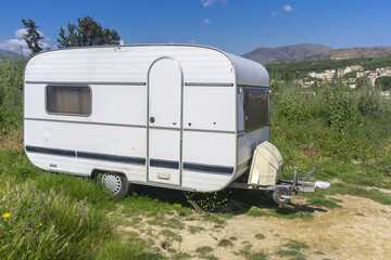 White caravan or camper trailer parked on country road in mountains. Camping travel, countryside travel.