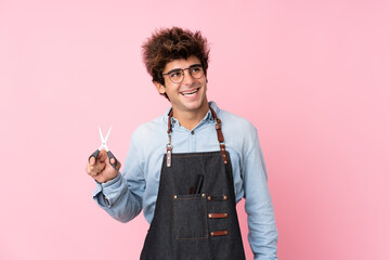 Young caucasian man over isolated pink background with hairdresser or barber dress looking up