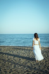 Fototapeta na wymiar Girl dressed in white with her back to the beach