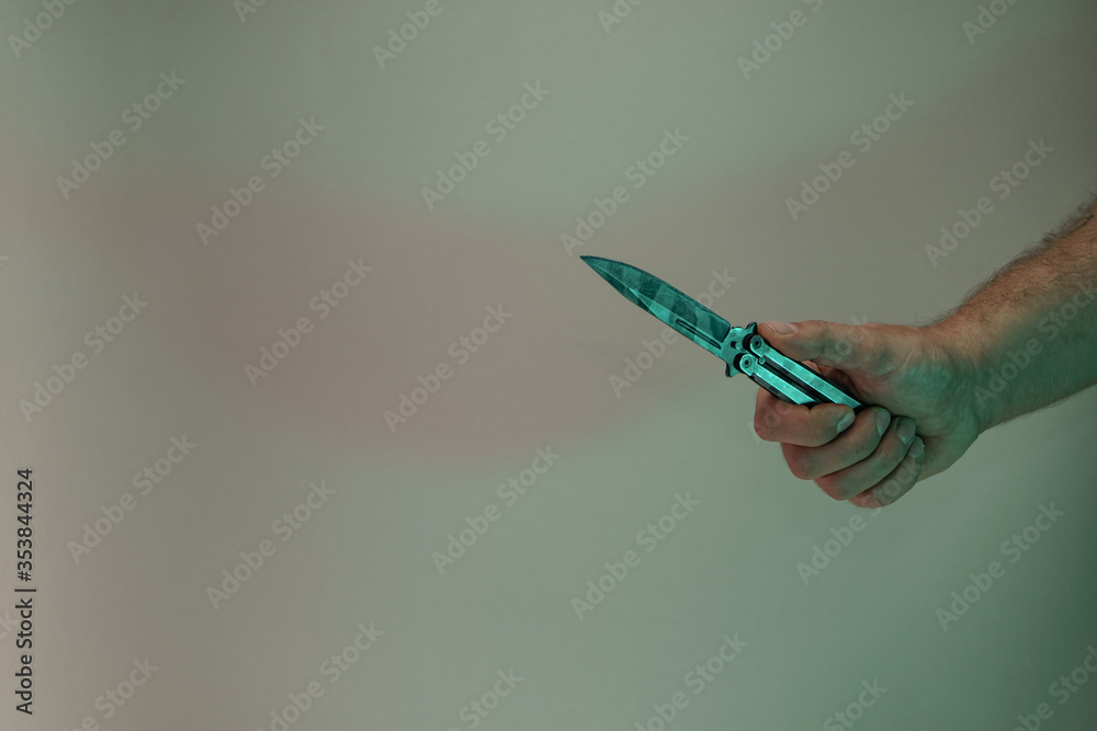 Poster Hand holding old butterfly knife in the color light. Beautiful old minimal in neon light. Minimalism retro style concept. Background pattern for design.