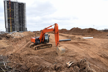 Red excavator during earthmoving at construction site. Backhoe dig ground for the construction of...