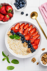 Oatmeal with strawberries, blueberries and walnuts. Healthy breakfast. Top view