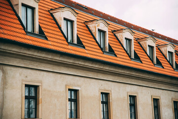 Photo of a part of an european facade with windows and brick roof