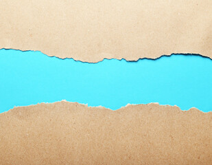 Dark paper with torn edges isolated on a blue background of colored paper inside. Good paper texture