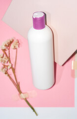 White plastic bottle, container for shampoo and cosmetics with place for inscription on pink background.