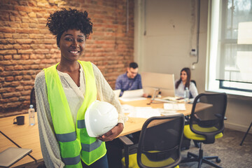 Young architect holding hardhat and blue print. Young attractive architect working in modern office. Businesswoman, Architect, Blueprint, Engineer. Business woman with project