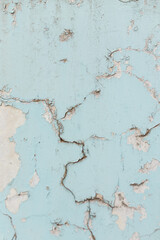 Texture of cracked wall with light blue paint, background or backdrop of abandoned building exterior.