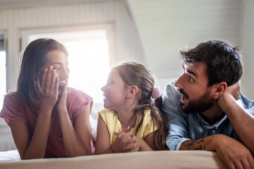 Family lying on bed in beedroom.