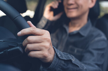 Smiling asian business man using mobile phone calling while driving a car © tippapatt