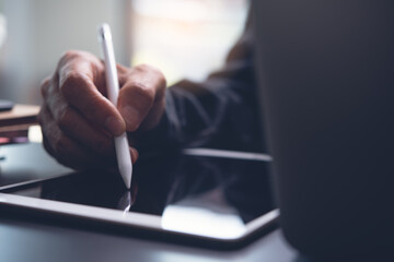 Closeup of man hand using stylus pen touching on digital tablet screen